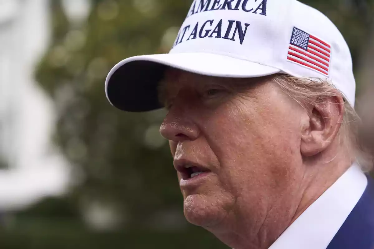 Hombre de perfil usando una gorra blanca con una bandera de Estados Unidos y letras azules Hombre de perfil usando una gorra blanca con una bandera de Estados Unidos y letras azules