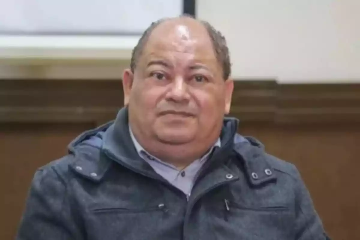 Hombre de mediana edad con chaqueta gris sentado en un ambiente interior