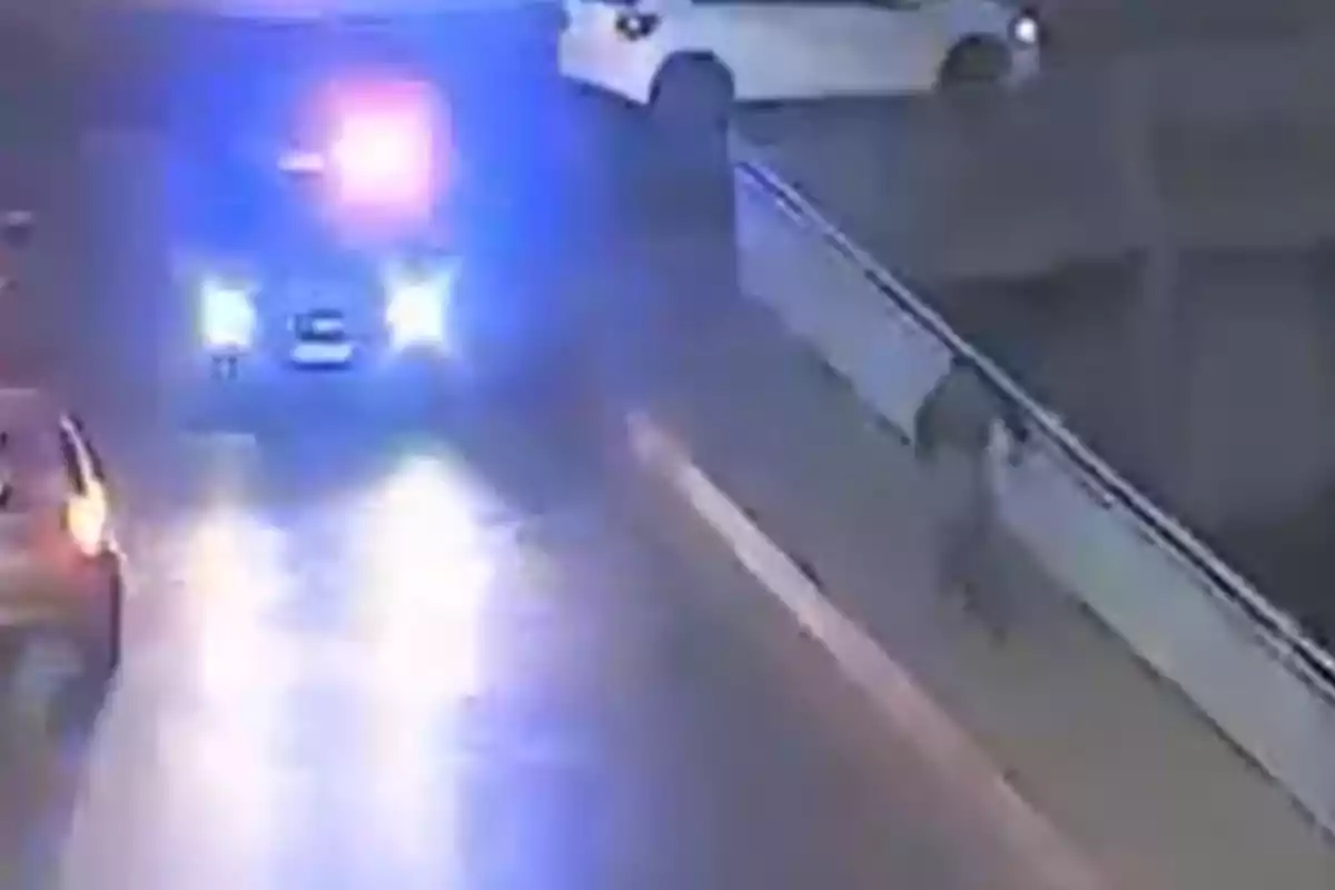 Patrol car with lights on chasing a person running next to a barrier on a street at night Patrol car with lights on chasing a person running next to a barrier on a street at night