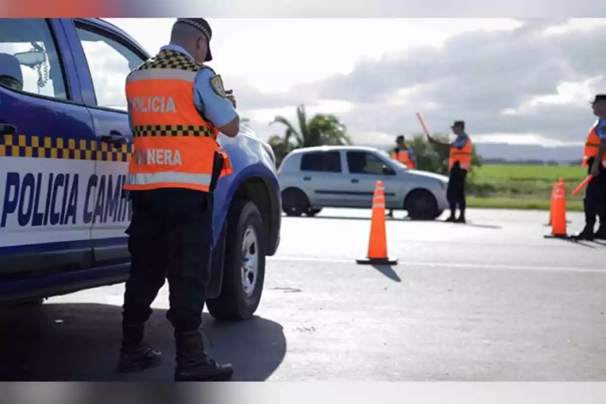 Policías viales realizan un control de tránsito en una carretera con conos naranjas y un auto detenido Policías viales realizan un control de tránsito en una carretera con conos naranjas y un auto detenido