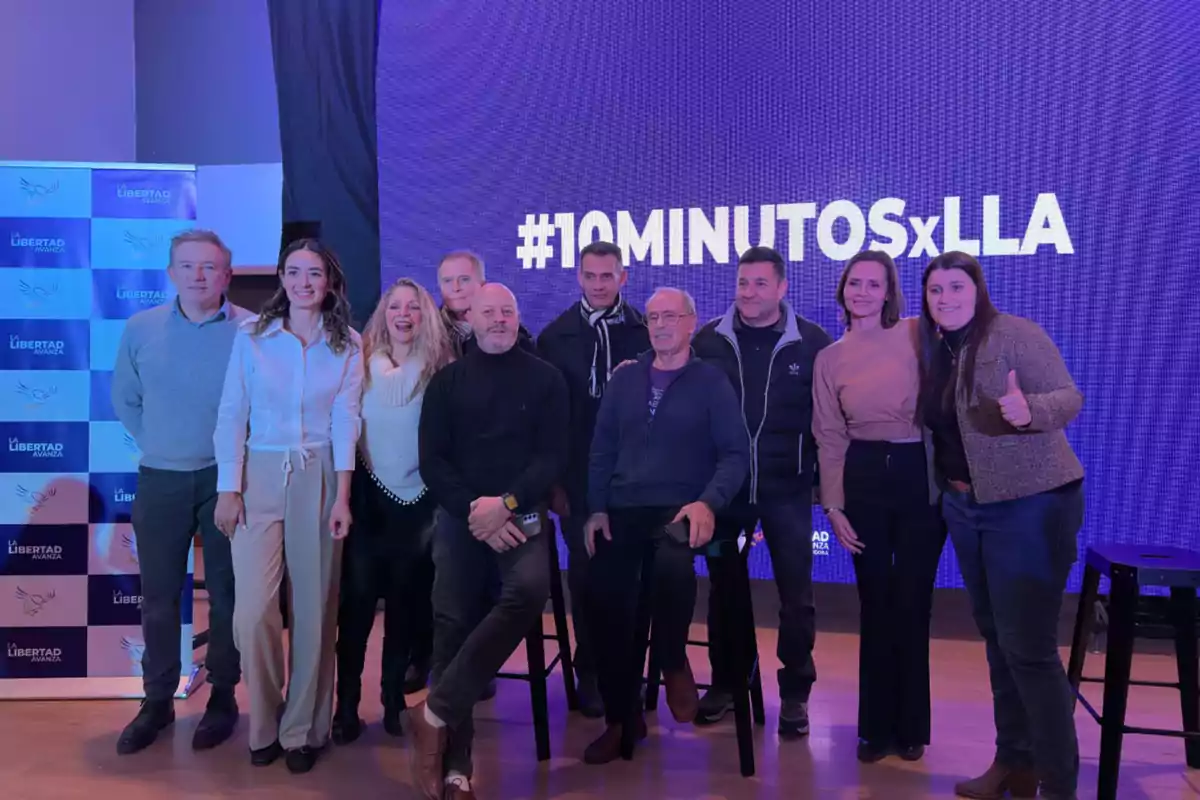 Grupo de personas posando juntas en un evento con un fondo azul que tiene el texto 10MINUTOSxLLA y un cartel de La Libertad Avanza a la izquierda Grupo de personas posando juntas en un evento con un fondo azul que tiene el texto 10MINUTOSxLLA y un cartel de La Libertad Avanza a la izquierda