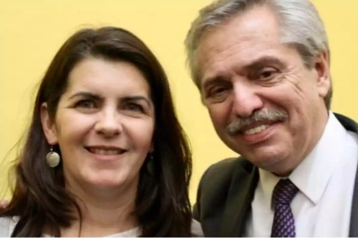 Dos personas sonríen frente a una pared amarilla Dos personas sonríen frente a una pared amarilla
