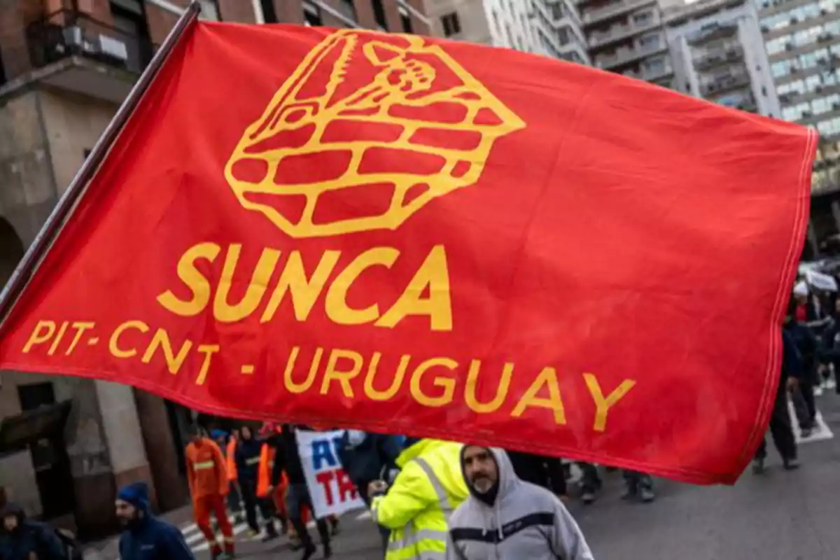 Bandera roja del sindicato SUNCA de Uruguay sostenida durante una manifestación en la calle