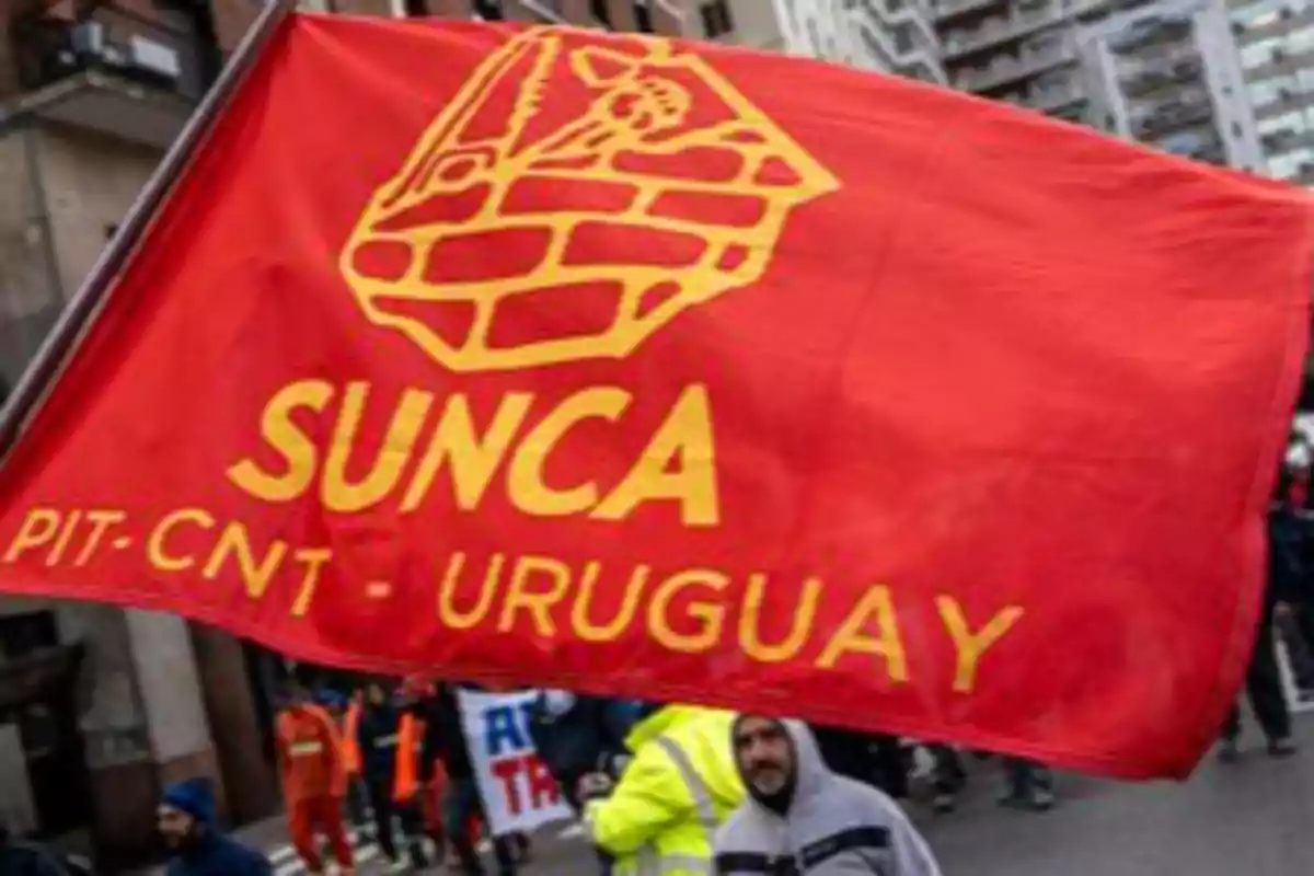 Bandera roja del sindicato SUNCA de Uruguay sostenida por manifestantes en una marcha urbana Bandera roja del sindicato SUNCA de Uruguay sostenida por manifestantes en una marcha urbana