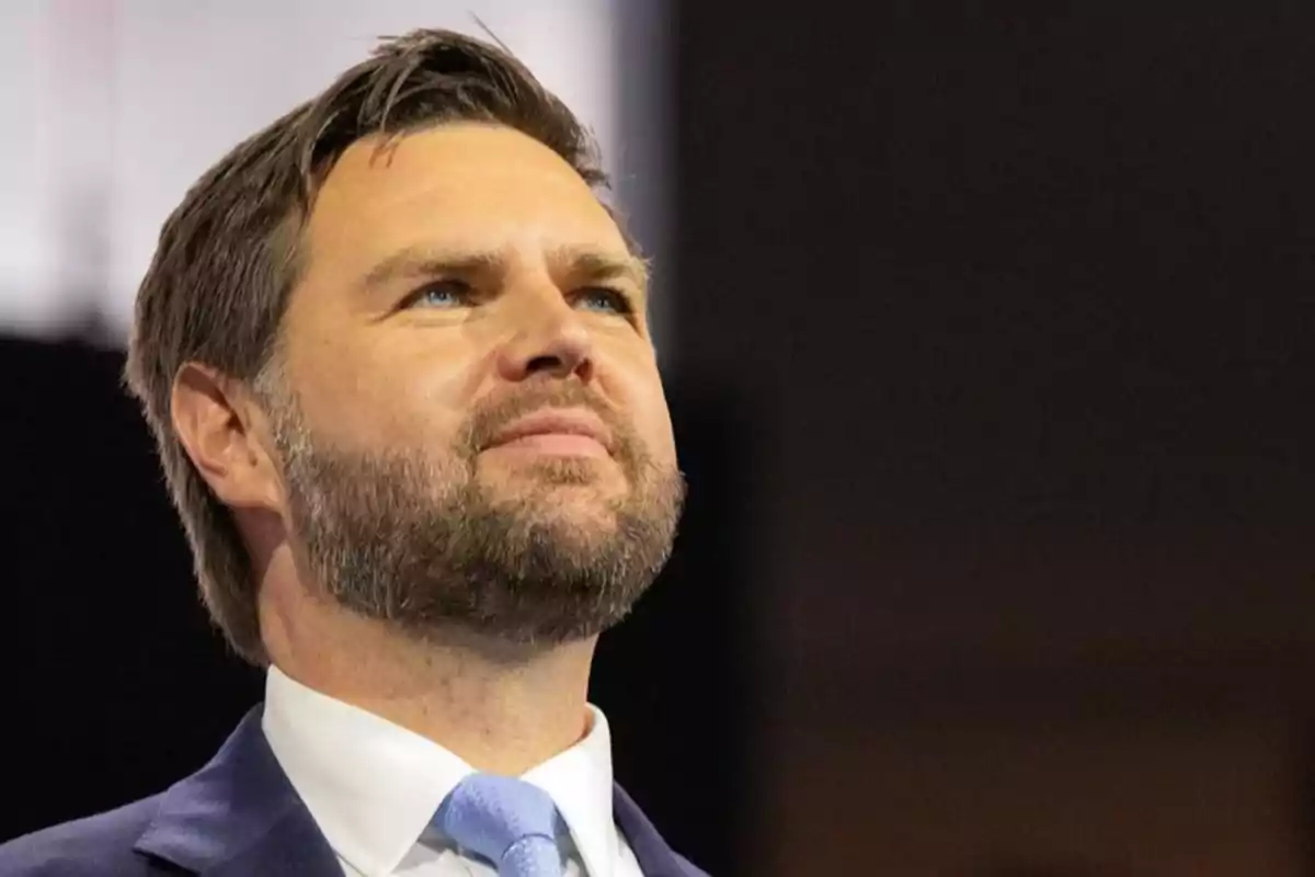 Hombre de barba y cabello corto con traje azul y corbata celeste mirando hacia arriba con expresión seria Hombre de barba y cabello corto con traje azul y corbata celeste mirando hacia arriba con expresión seria