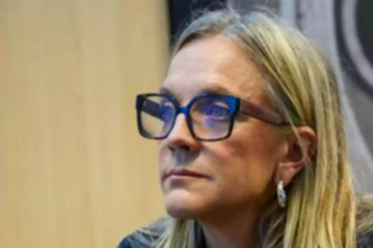 Blonde-haired woman with large glasses looks alertly ahead Blonde-haired woman with large glasses looks alertly ahead