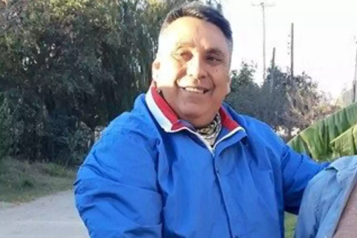Hombre sonriente con chaqueta azul al aire libre en un entorno natural Hombre sonriente con chaqueta azul al aire libre en un entorno natural
