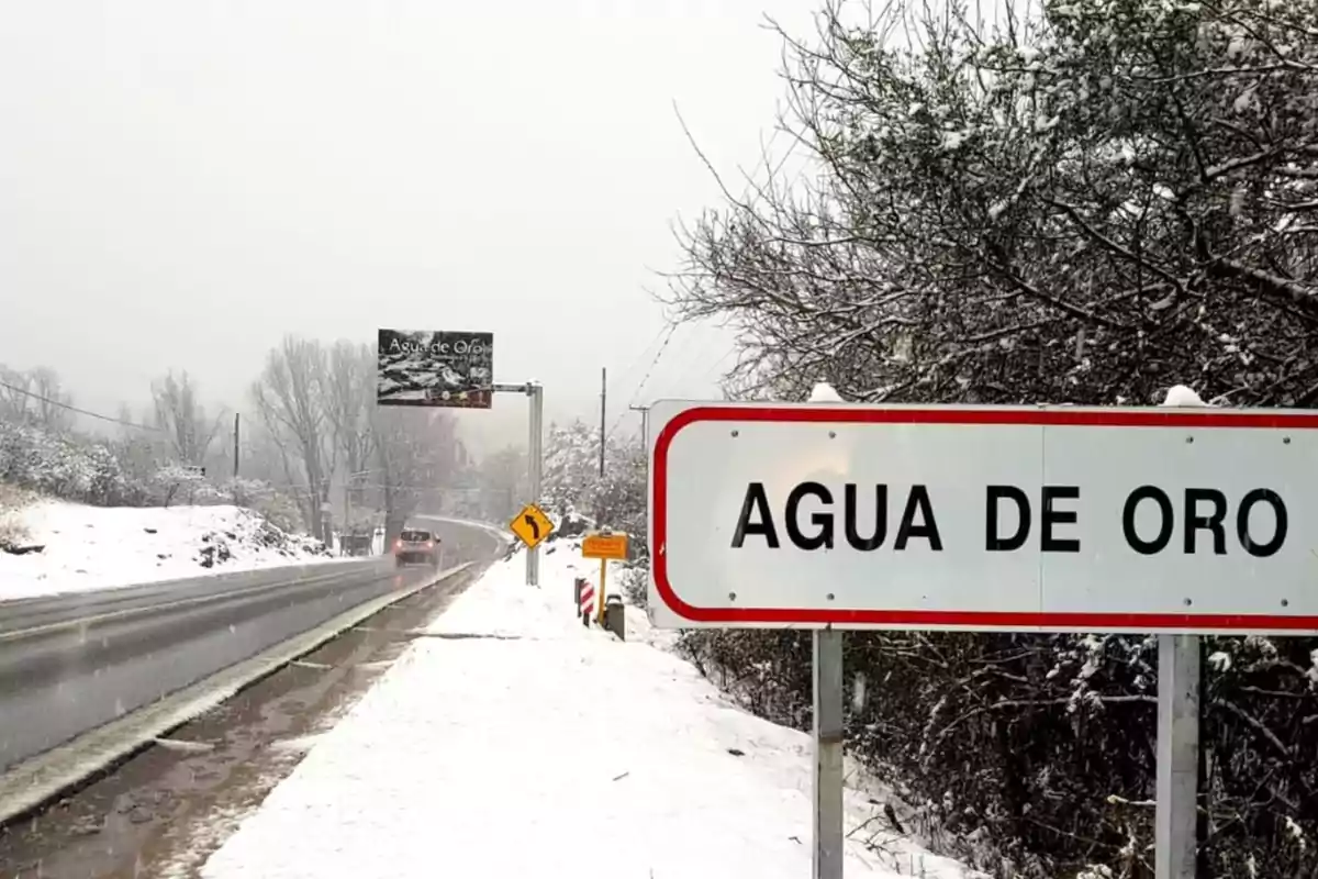 Welcome sign to Agua de Oro next to a snow-covered road and snow-covered trees on a cloudy day Welcome sign to Agua de Oro next to a snow-covered road and snow-covered trees on a cloudy day