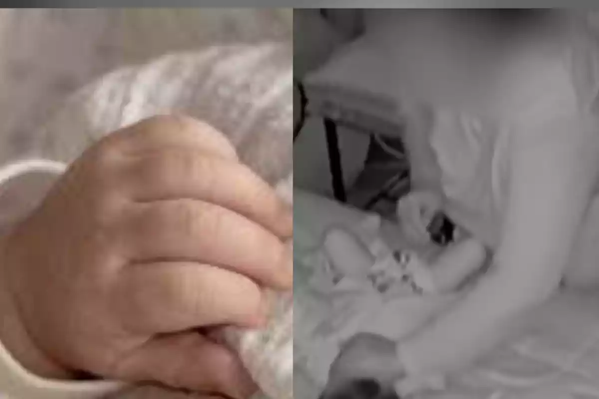 A baby's hand holding a blanket and a person sitting next to a baby on a bed