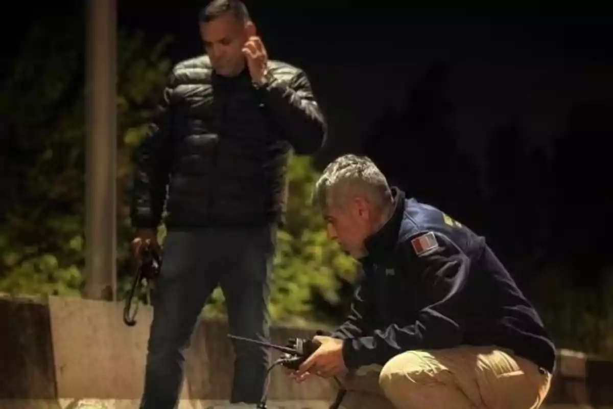 Dos hombres con ropa abrigadora y equipo de comunicación trabajan al aire libre durante la noche