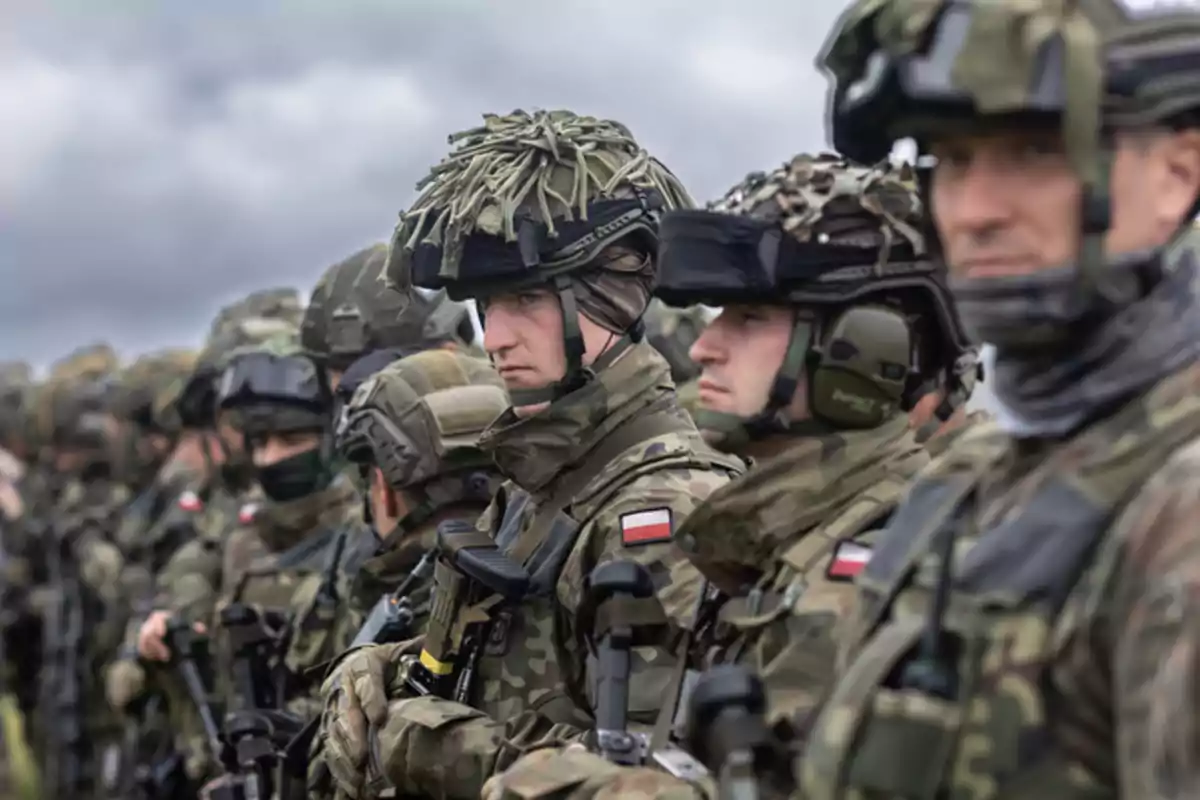 Soldiers in camouflage uniforms and helmets lined up in formation under a cloudy sky Soldiers in camouflage uniforms and helmets lined up in formation under a cloudy sky