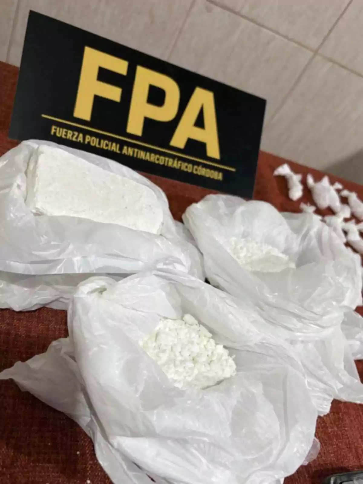 Plastic bags with white substances on a table and a Córdoba Anti-Narcotics Police Force sign in the background Plastic bags with white substances on a table and a Córdoba Anti-Narcotics Police Force sign in the background