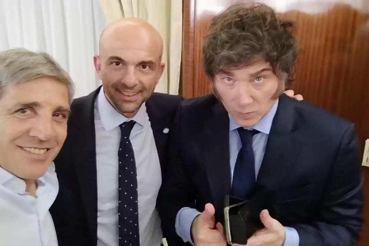 Three men dressed in suits pose together for a selfie in an elegant indoor setting.
