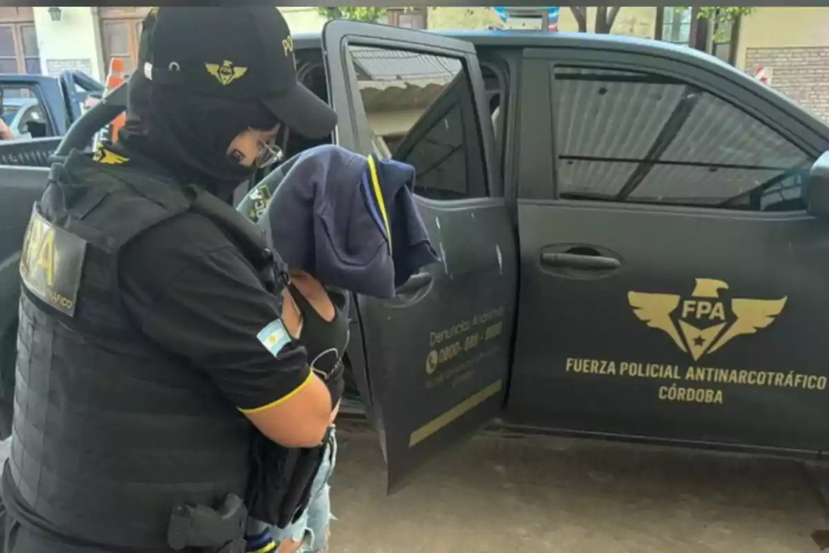 Policía de la Fuerza Policial Antinarcotráfico de Córdoba deteniendo a una persona junto a una camioneta oficial