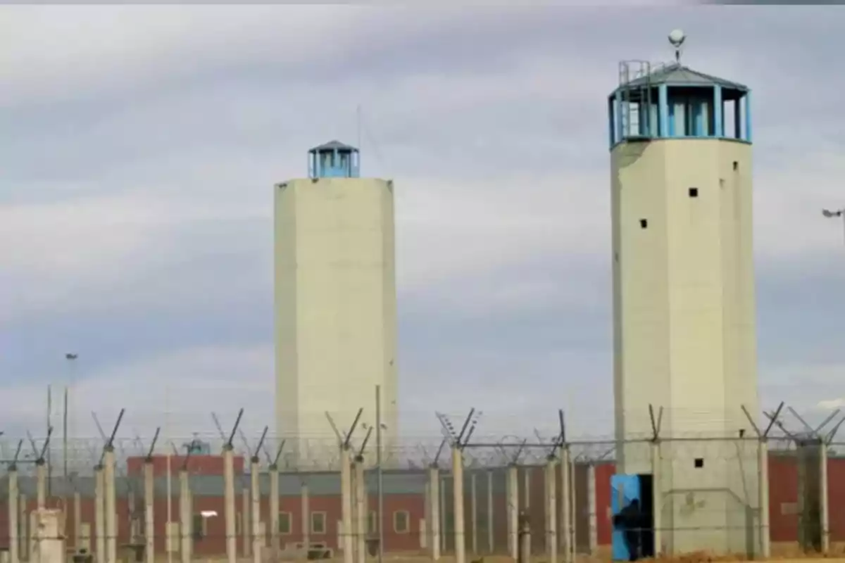 Torres de vigilancia altas y una cerca con alambre de púas rodeando un edificio de prisión