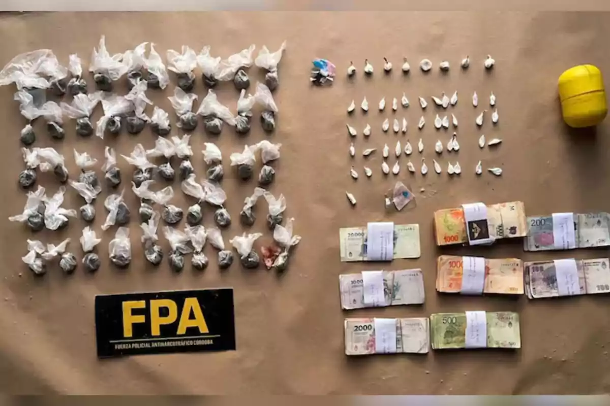 Sobre una superficie beige se observan varios envoltorios pequeños, billetes de diferentes denominaciones organizados en fajos, un recipiente amarillo y un cartel con las siglas FPA Sobre una superficie beige se observan varios envoltorios pequeños, billetes de diferentes denominaciones organizados en fajos, un recipiente amarillo y un cartel con las siglas FPA