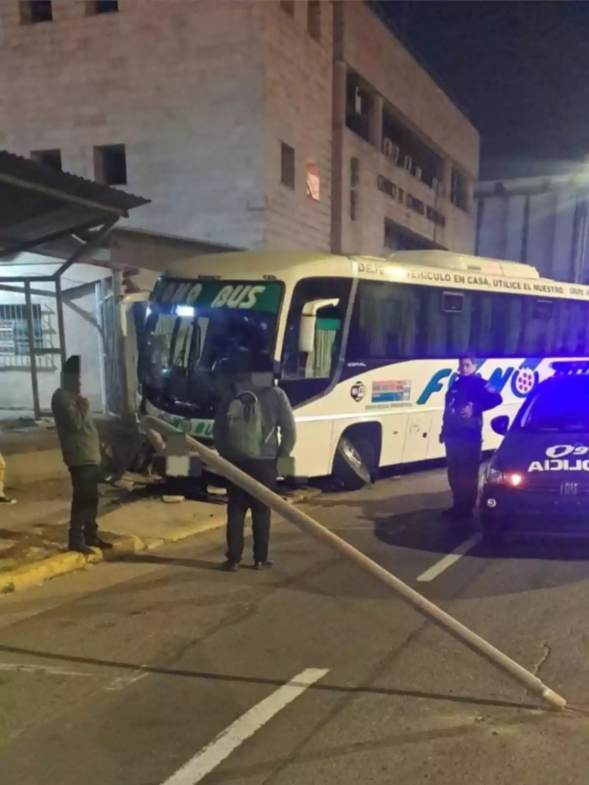A bus crashed into a sidewalk and a light pole fell to the ground while several people and a police patrol watch the scene. A bus crashed into a sidewalk and a light pole fell to the ground while several people and a police patrol watch the scene.