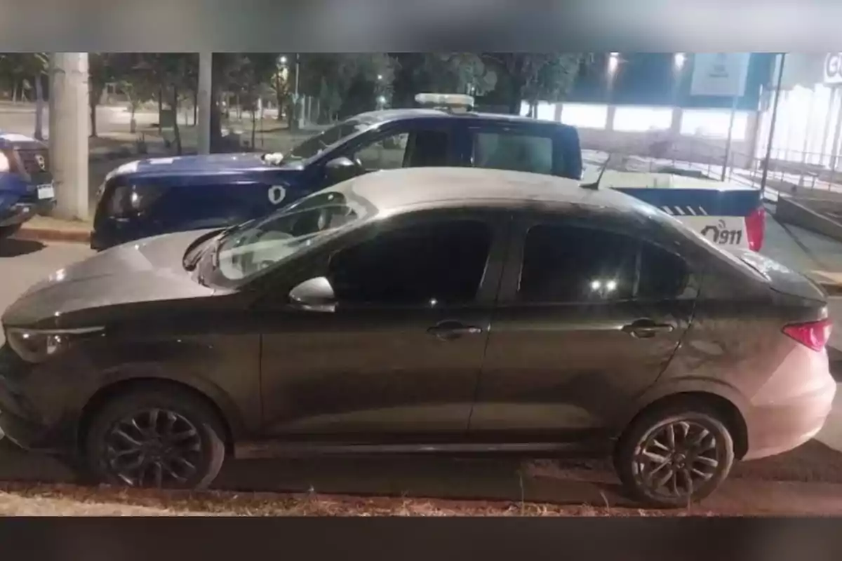Automóvil gris estacionado frente a una patrulla de policía en una calle por la noche Automóvil gris estacionado frente a una patrulla de policía en una calle por la noche
