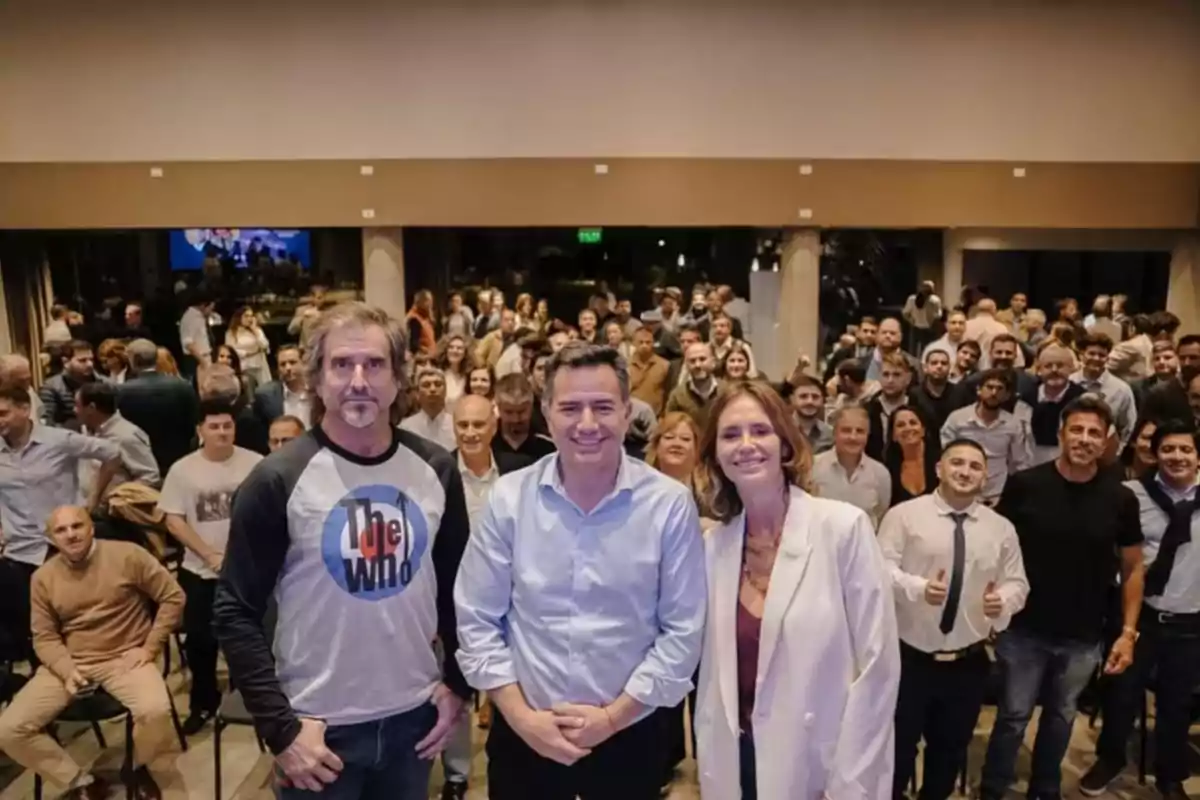A large group of people posing for a photo at a social or corporate event, with three people in the foreground smiling and the rest in the background. A large group of people posing for a photo at a social or corporate event, with three people in the foreground smiling and the rest in the background.