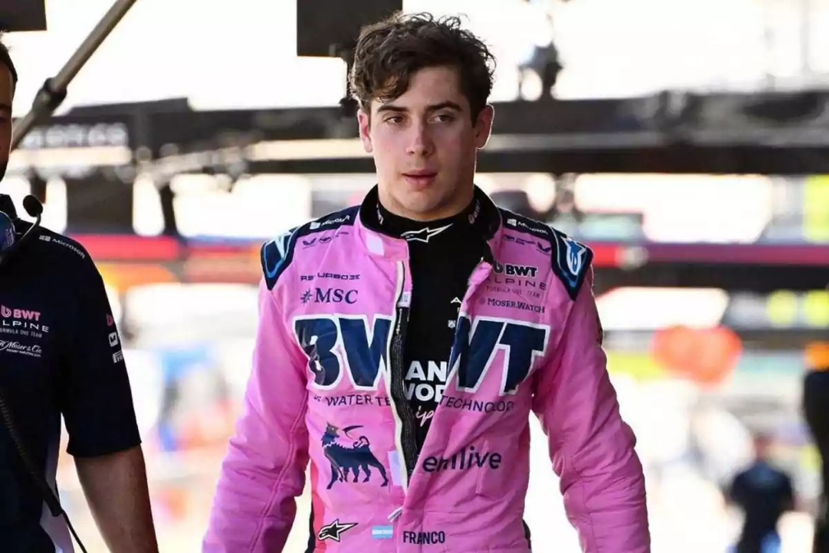 Motorsport driver wearing a pink racing suit from the BWT Alpine team in a race paddock