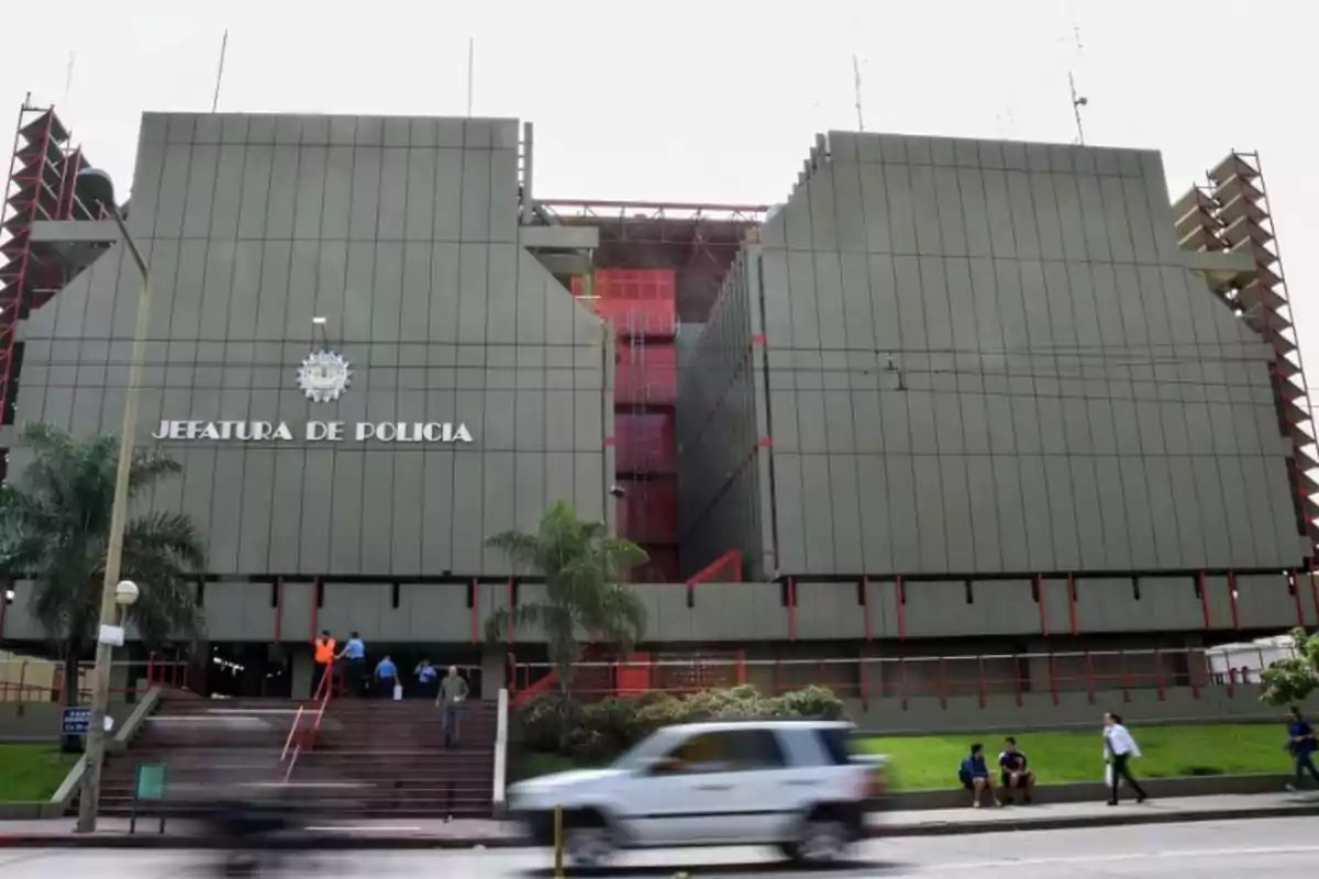 Edificio grande de la jefatura de policía con personas entrando y saliendo y autos pasando por la calle frente a la entrada principal Edificio grande de la jefatura de policía con personas entrando y saliendo y autos pasando por la calle frente a la entrada principal