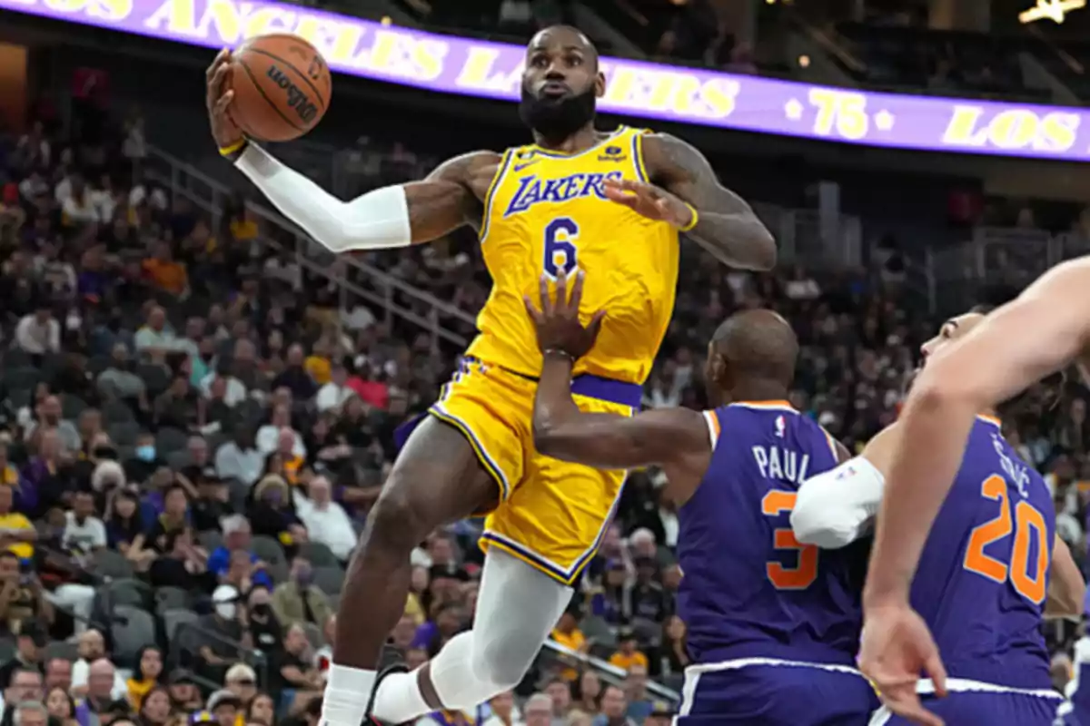 Lakers player with the ball jumps toward the basket while being defended by Suns players during a basketball game.