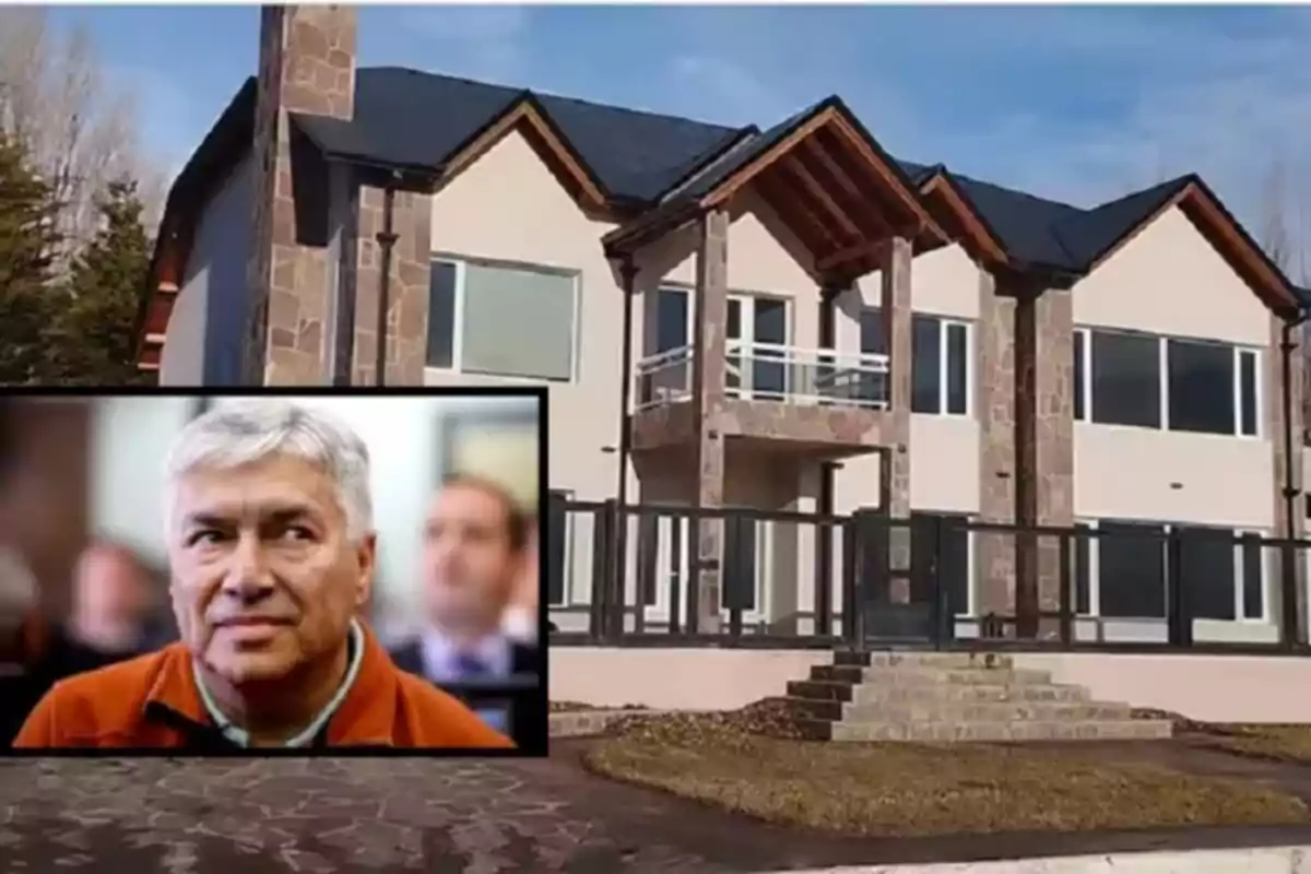 Facade of a large two-story house with stone details and a dark roof; in the lower left corner, there is a box showing a man with gray hair and a serious expression.