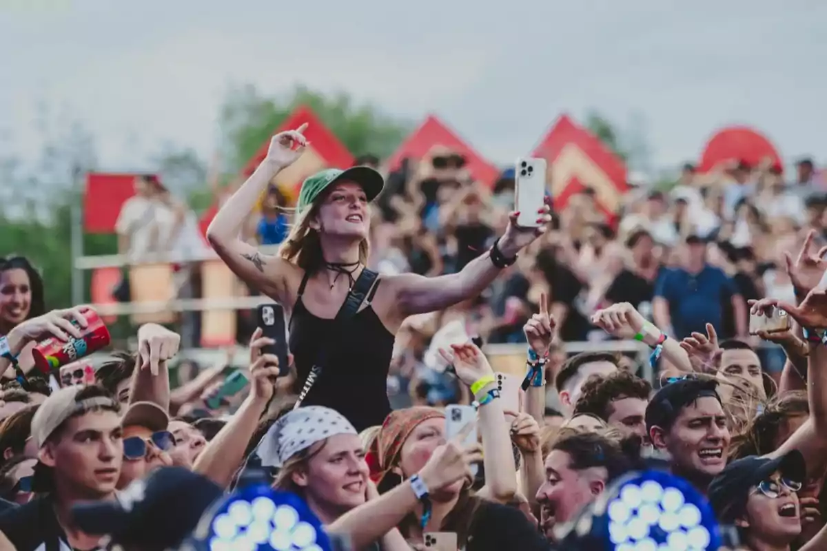 Jóvenes disfrutando de un concierto al aire libre mientras una chica se toma una selfie entre la multitud