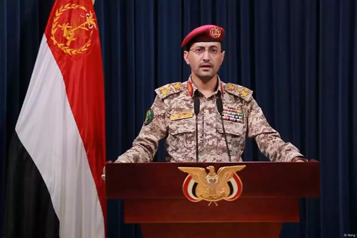 A soldier in camouflage uniform and a red beret gives a speech at a podium with the national emblem and a tricolor flag behind him. A soldier in camouflage uniform and a red beret gives a speech at a podium with the national emblem and a tricolor flag behind him.