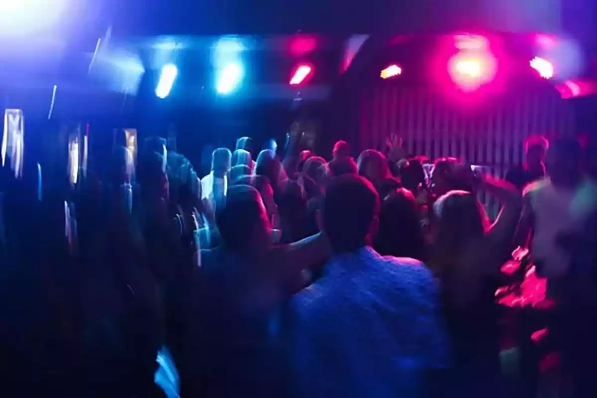 Personas bailando en una discoteca con luces de colores y ambiente animado Personas bailando en una discoteca con luces de colores y ambiente animado