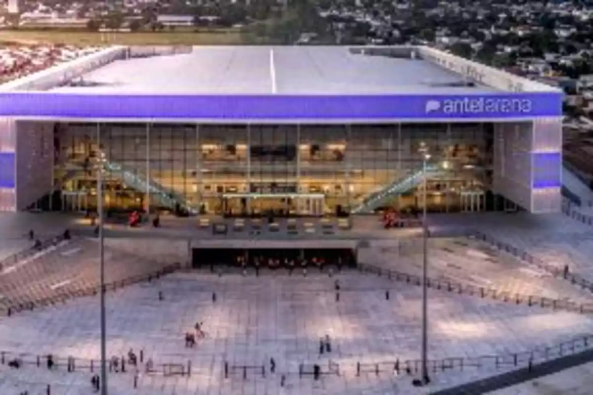 Front view of the Antel Arena illuminated at sunset with people walking on the main esplanade Front view of the Antel Arena illuminated at sunset with people walking on the main esplanade