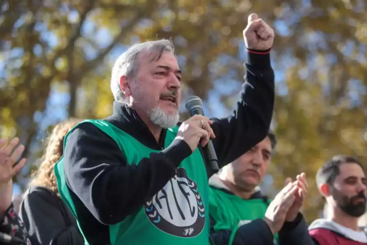Hombre de barba canosa hablando por micrófono y levantando el puño durante una manifestación, rodeado de otras personas con chalecos verdes Hombre de barba canosa hablando por micrófono y levantando el puño durante una manifestación, rodeado de otras personas con chalecos verdes