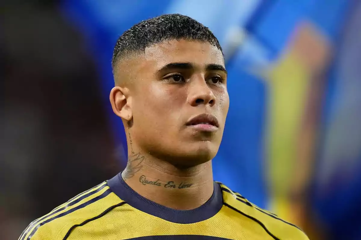Joven futbolista con camiseta amarilla y detalles azules mirando hacia el frente con fondo desenfocado Joven futbolista con camiseta amarilla y detalles azules mirando hacia el frente con fondo desenfocado