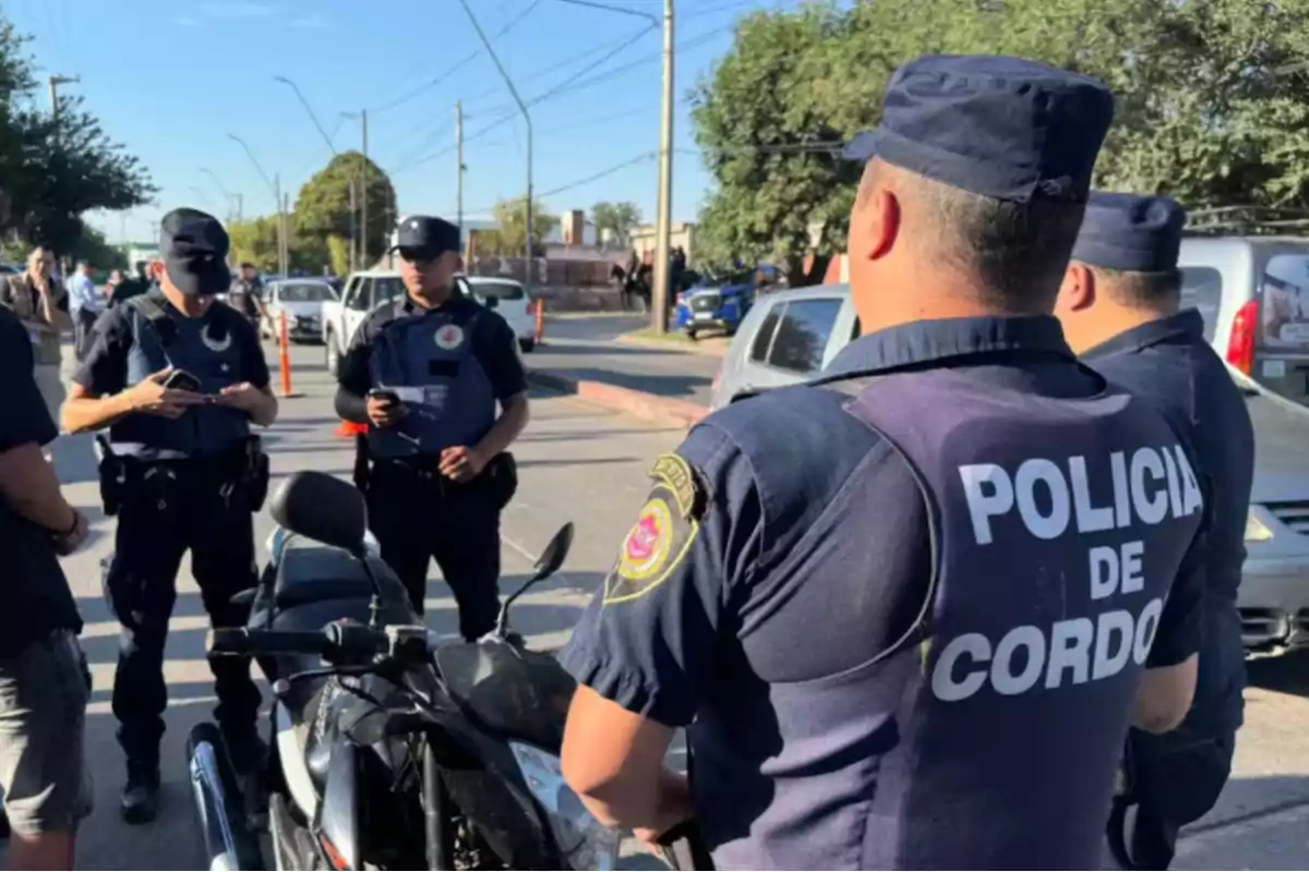 Several police officers from Córdoba are gathered on the street next to a motorcycle during a vehicle inspection operation in an urban area.