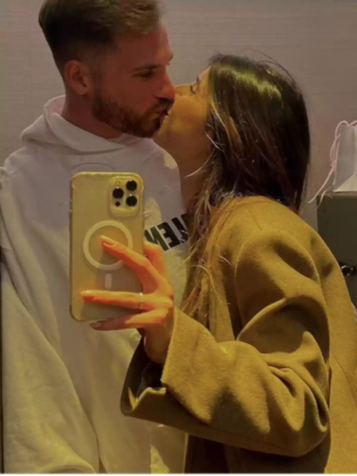 Pareja besándose mientras se toman una selfie frente a un espejo Pareja besándose mientras se toman una selfie frente a un espejo