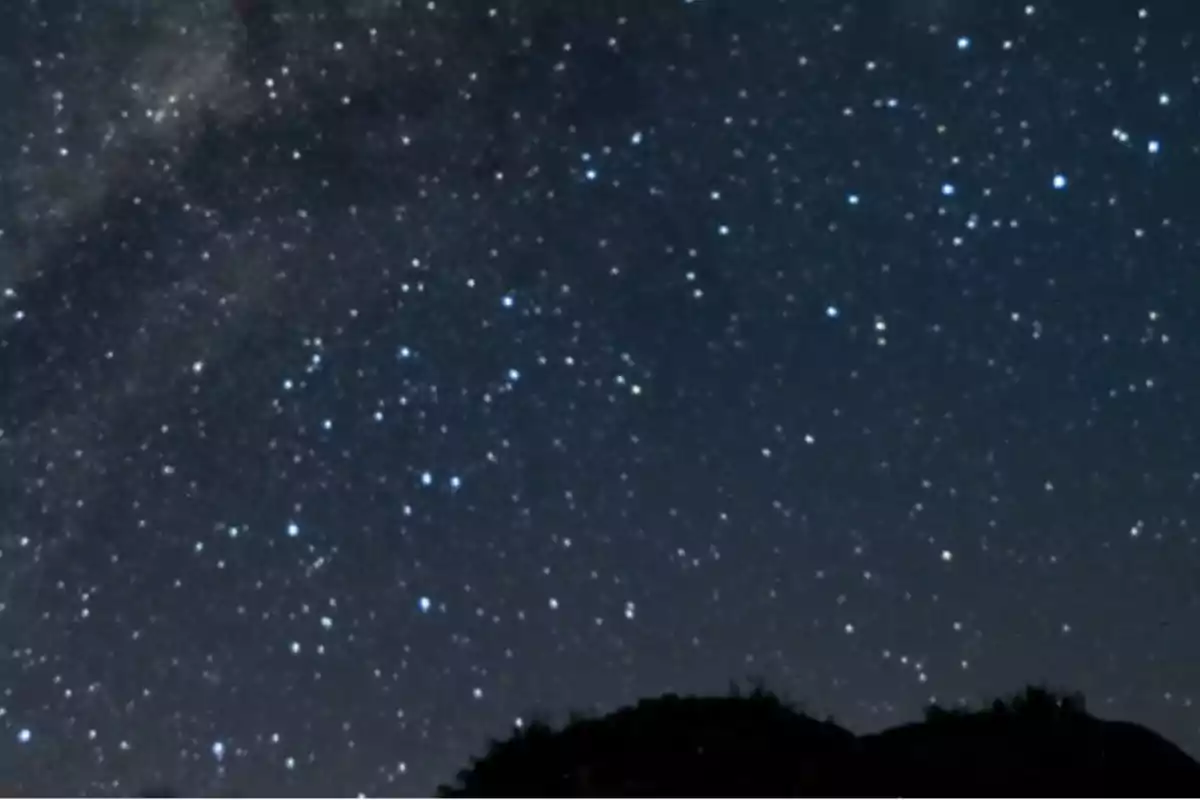 Cielo nocturno estrellado con silueta de colina en primer plano Cielo nocturno estrellado con silueta de colina en primer plano