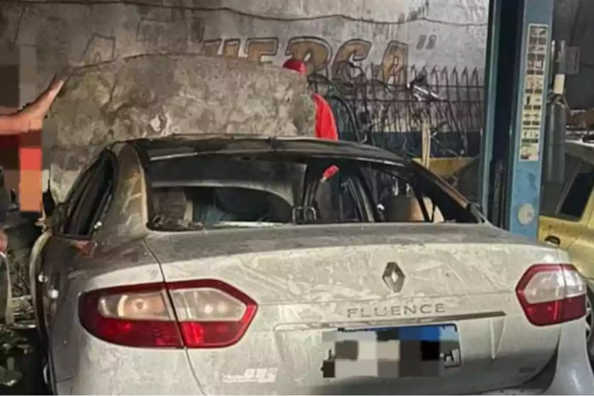 Auto Renault Fluence cubierto de polvo con la cajuela abierta en un taller mecánico Auto Renault Fluence cubierto de polvo con la cajuela abierta en un taller mecánico