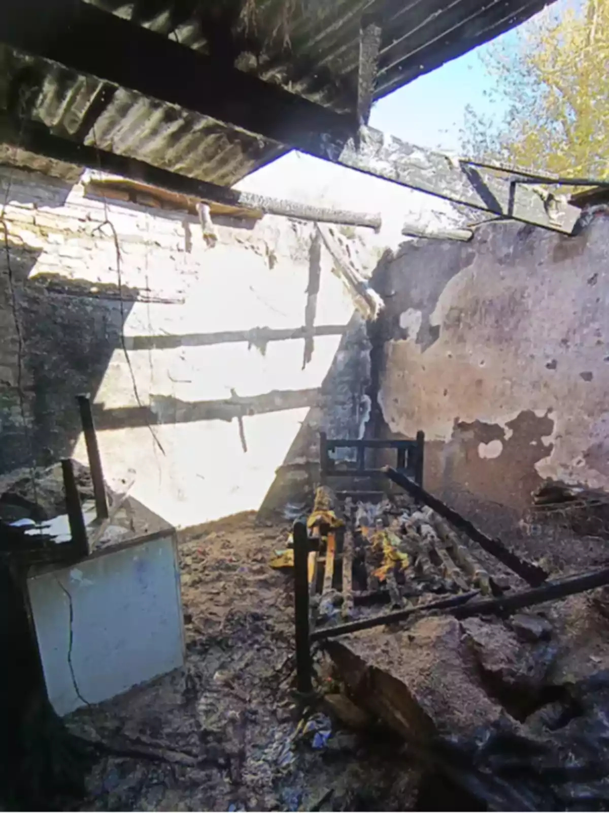 Habitación con paredes y techo quemados, cama destruida y restos de muebles calcinados tras un incendio Habitación con paredes y techo quemados, cama destruida y restos de muebles calcinados tras un incendio