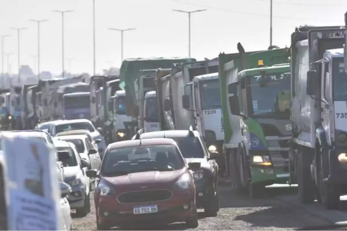 Tráfico intenso con varios camiones y autos detenidos en una avenida durante el día Tráfico intenso con varios camiones y autos detenidos en una avenida durante el día