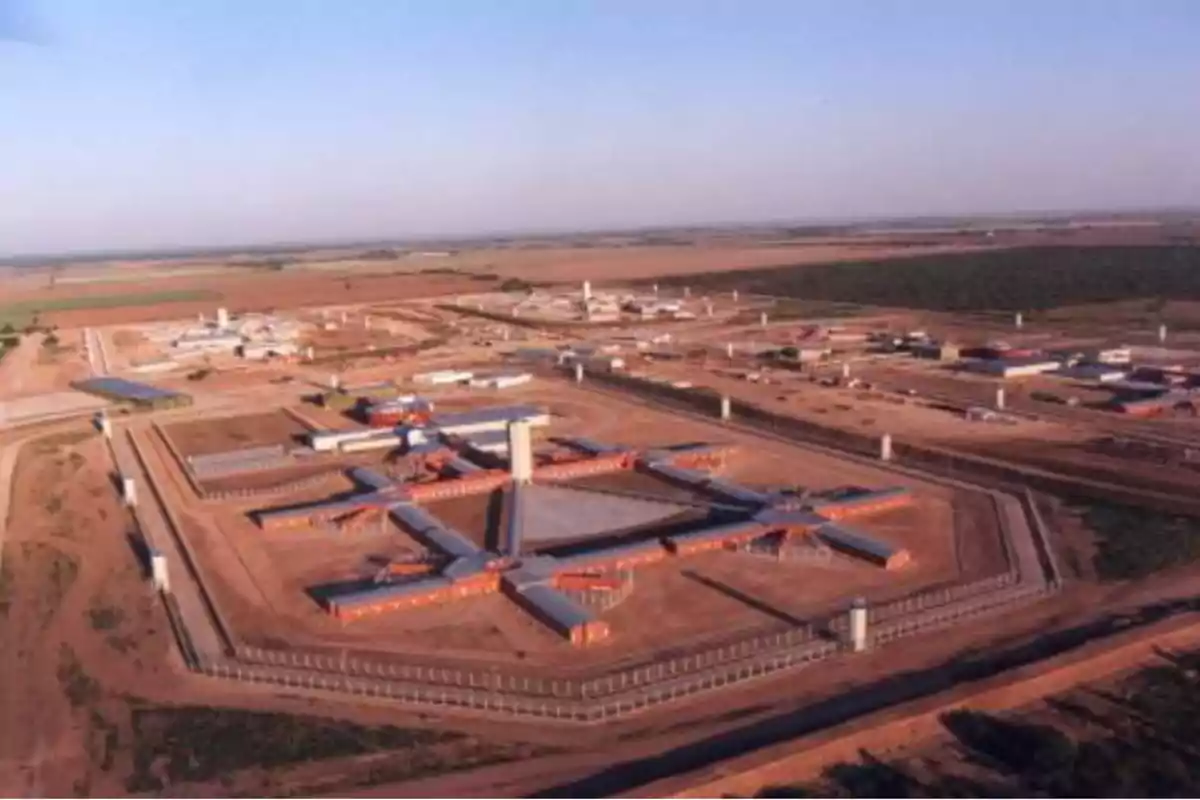 Aerial view of a high-security prison surrounded by walls and watchtowers in a rural area Aerial view of a high-security prison surrounded by walls and watchtowers in a rural area