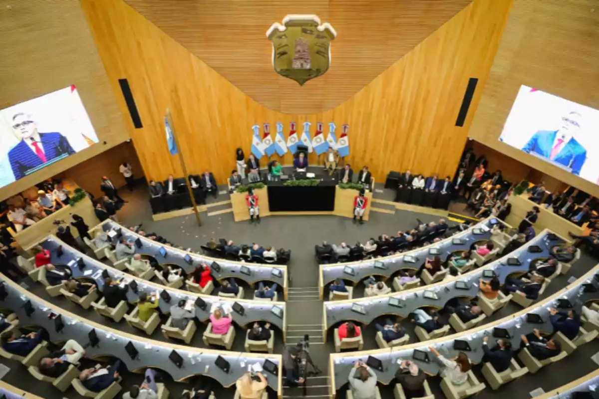 Vista panorámica de un recinto legislativo con personas sentadas en escritorios semicirculares y banderas argentinas al fondo
