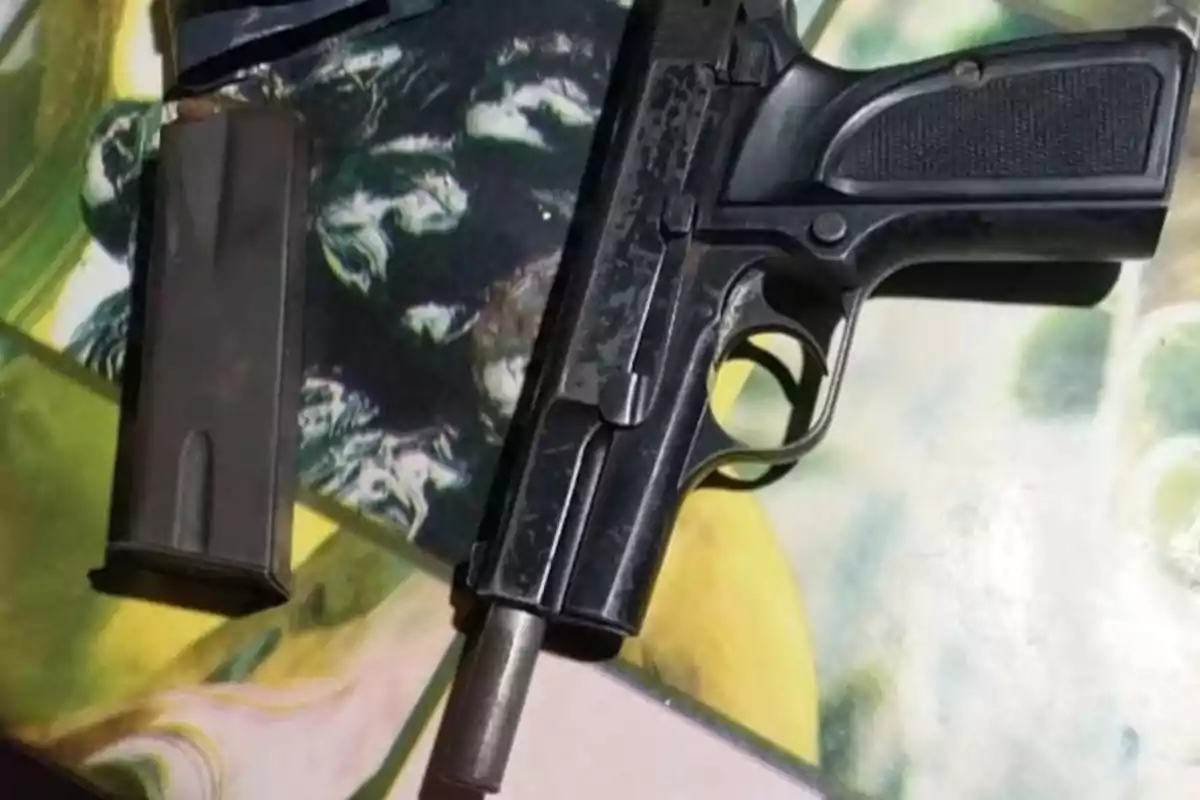 Pistola negra con el cargador separado sobre una superficie colorida
