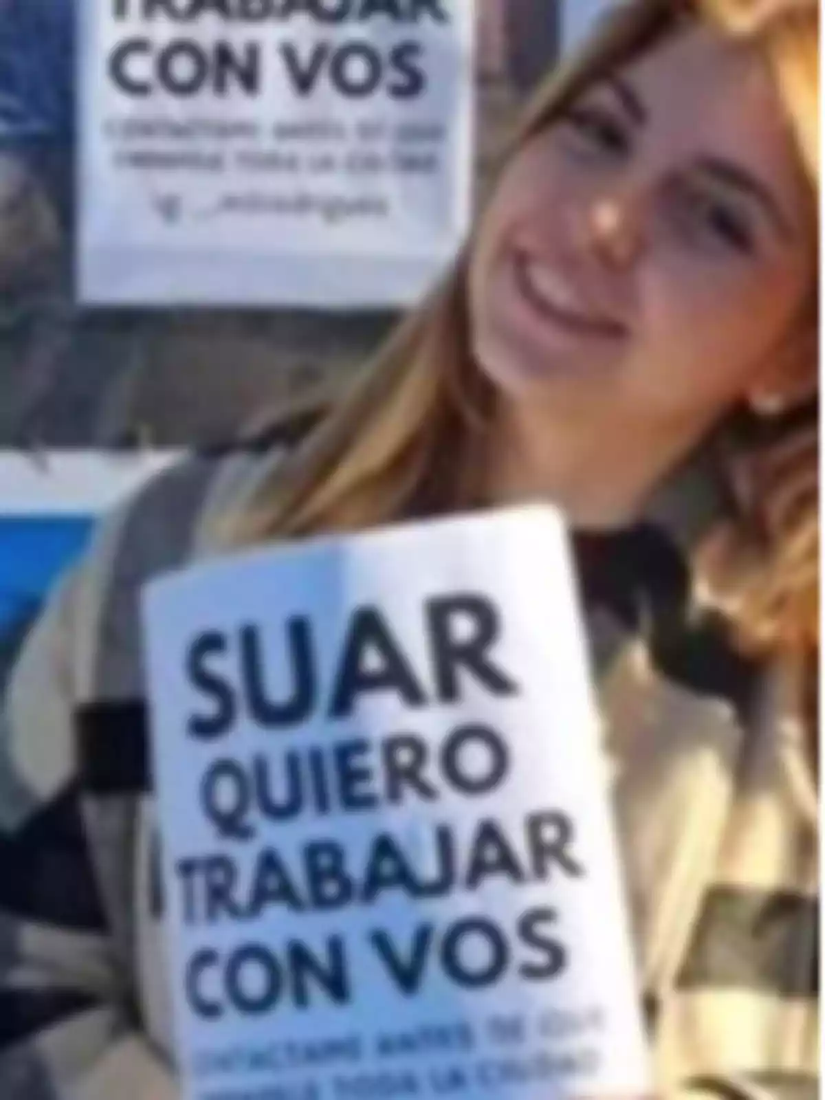 Joven sonriente sostiene un cartel que dice Suar quiero trabajar con vos