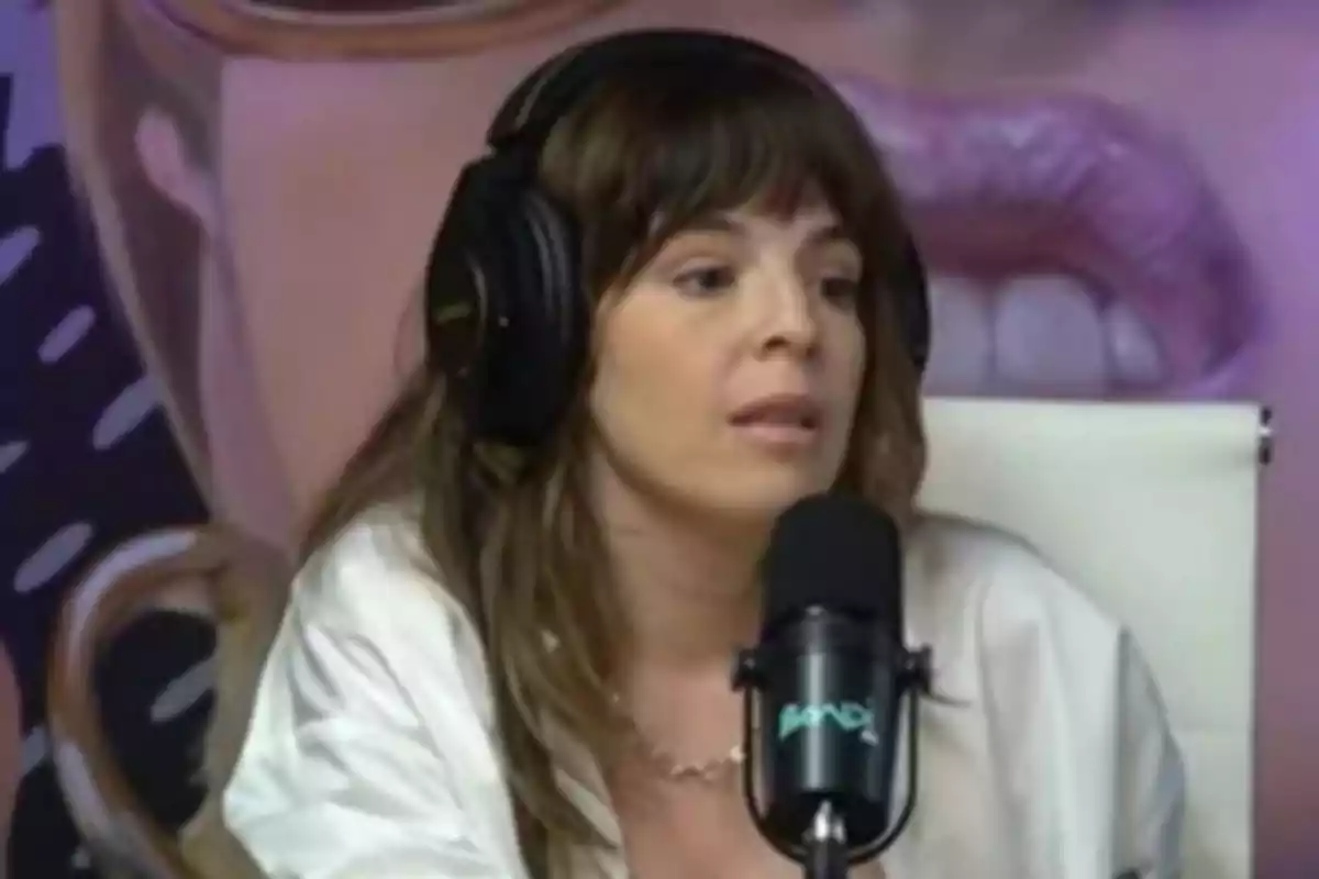 Mujer con auriculares grandes hablando frente a un micrófono en un estudio de grabación