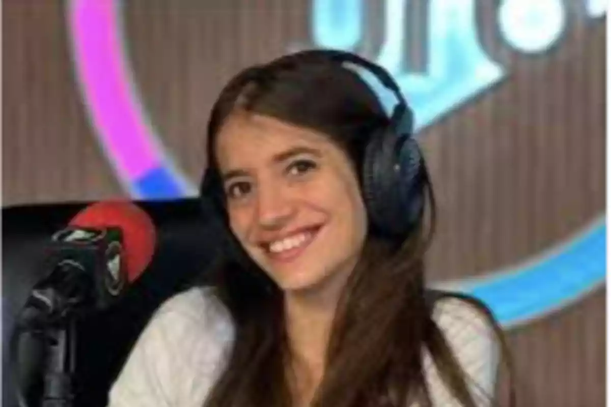 Mujer joven sonriendo con auriculares grandes frente a un micrófono en un estudio de radio