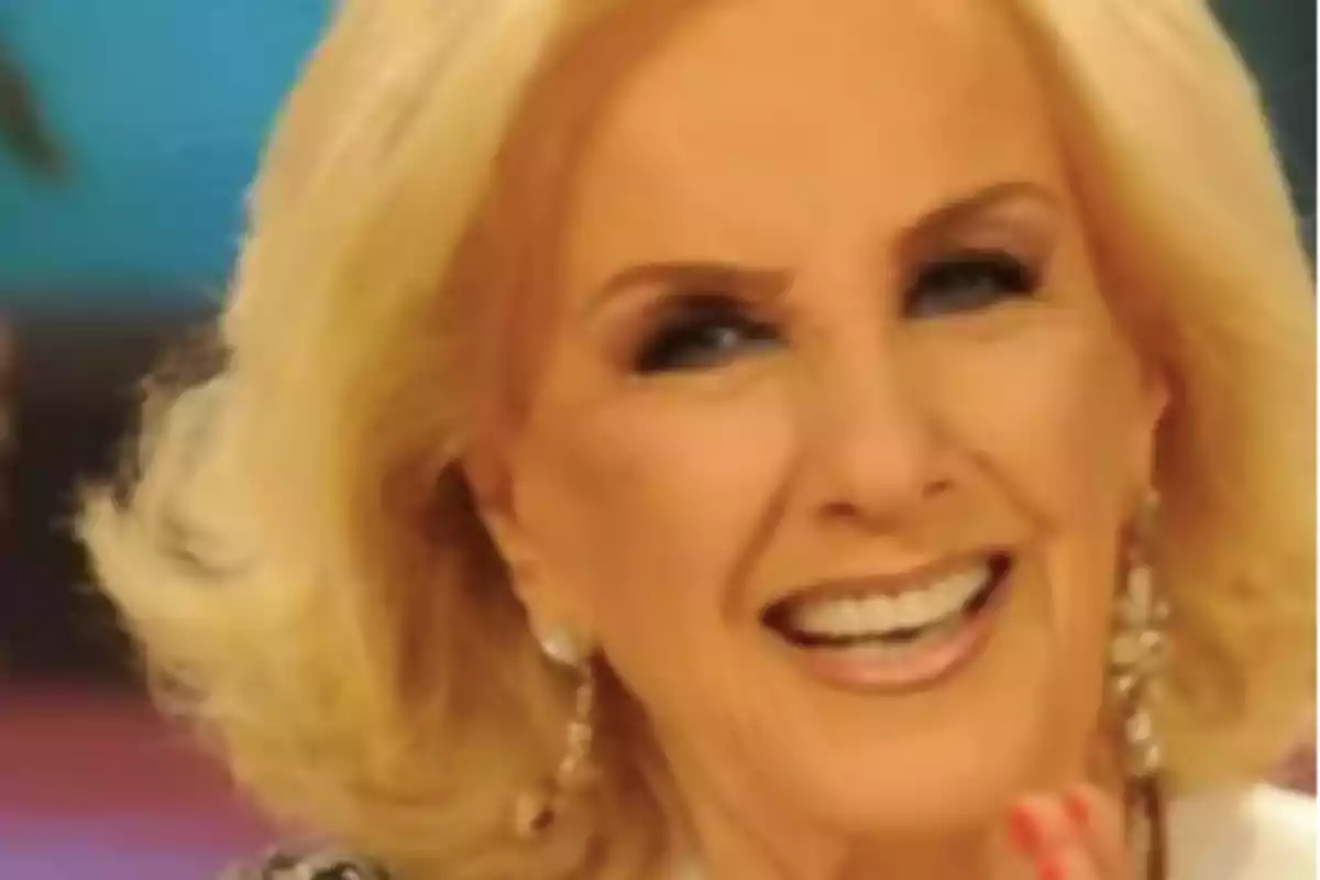 Mujer rubia de cabello corto sonriendo y usando aretes largos