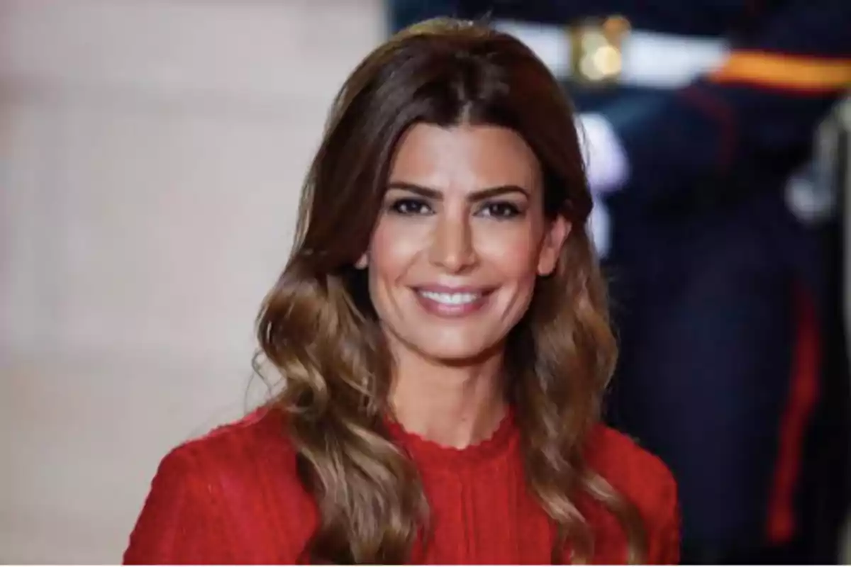 Mujer de cabello largo y ondulado con vestido rojo sonriendo frente a la cámara