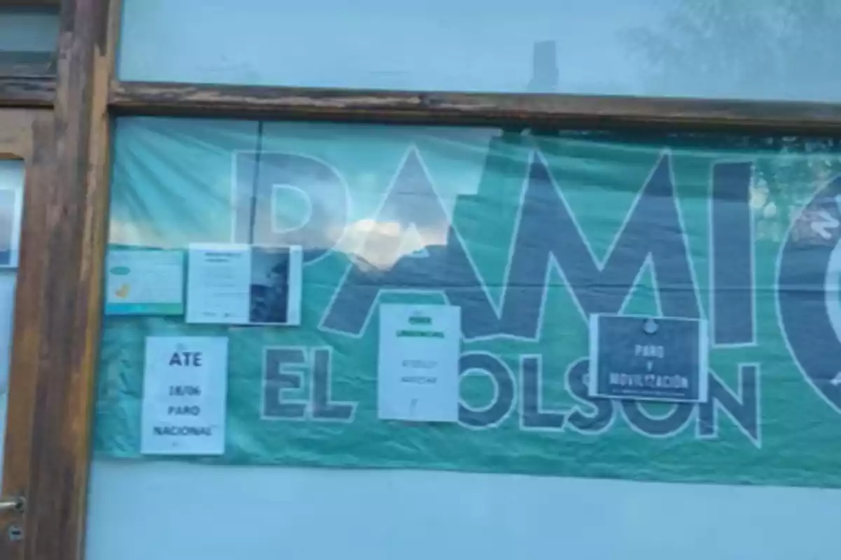 Cartel de una oficina de PAMI El Bolsón con varios avisos pegados en la ventana anunciando paro y movilización