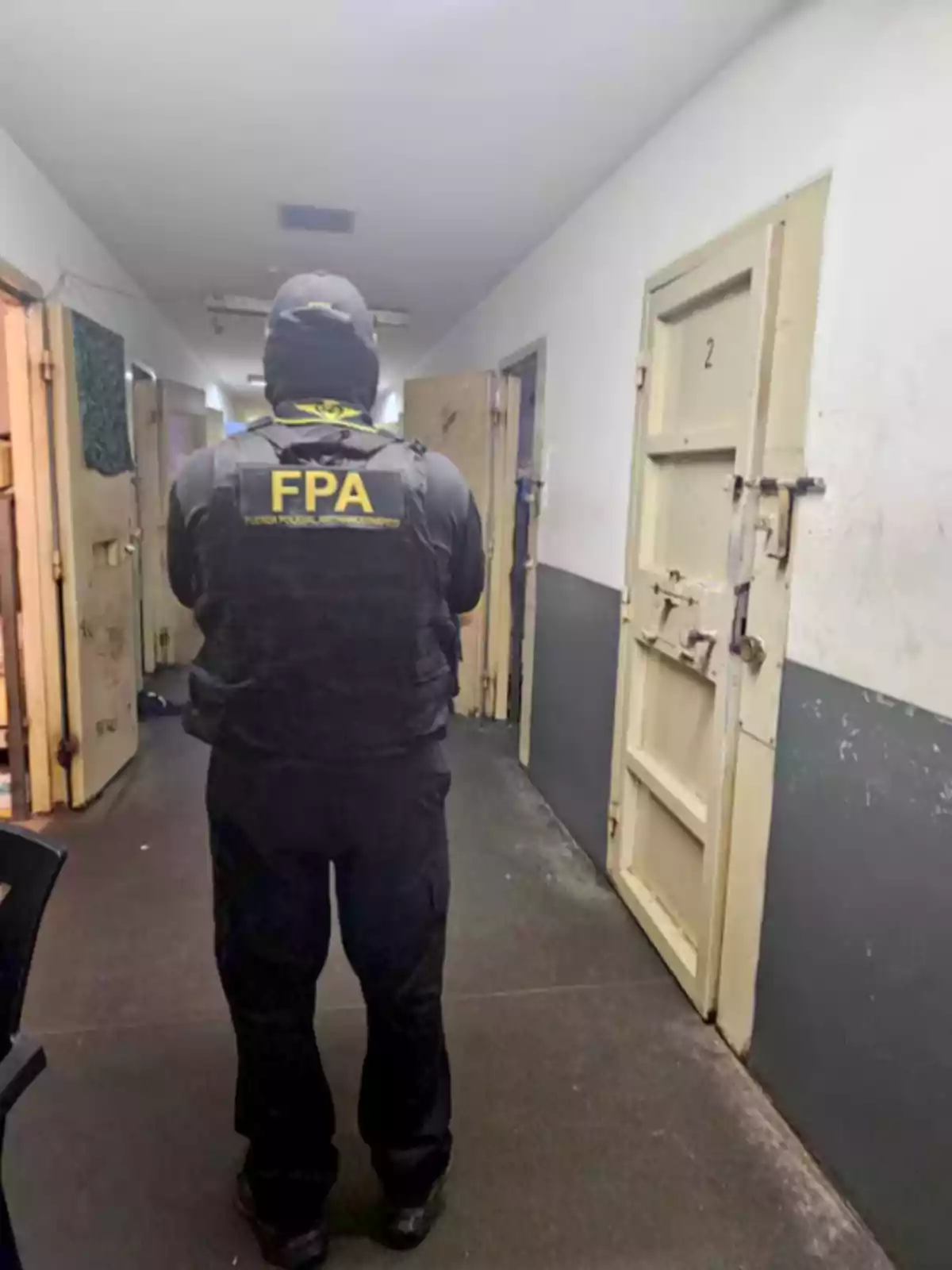 Anti-Narcotics Police Force agent with his back turned in a hallway of closed doors inside a building Anti-Narcotics Police Force agent with his back turned in a hallway of closed doors inside a building
