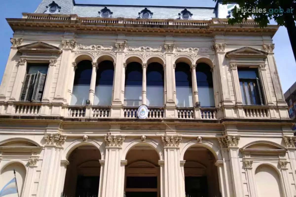 Fachada de un edificio antiguo de estilo clásico con columnas y arcos, bandera argentina y escudo oficial en el centro Fachada de un edificio antiguo de estilo clásico con columnas y arcos, bandera argentina y escudo oficial en el centro